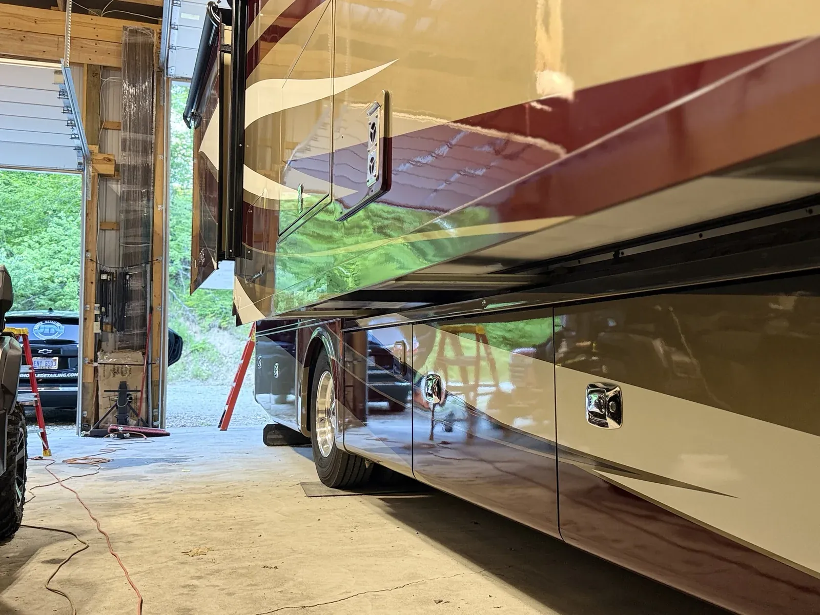 Glossy lower panels and compartment doors on a Class A motorhome after detailing, JTN unit in the background