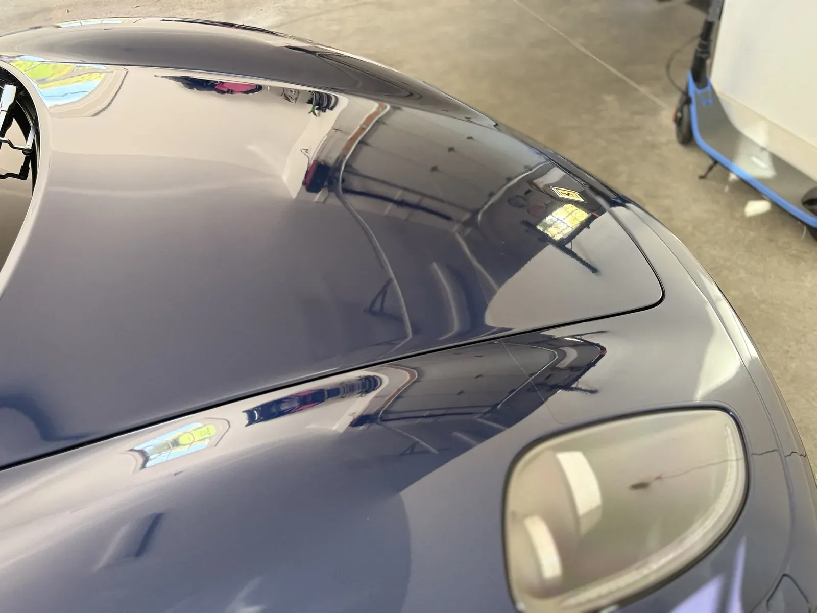 Deep gloss and sharp reflections on a blue Ferrari hood after detailing