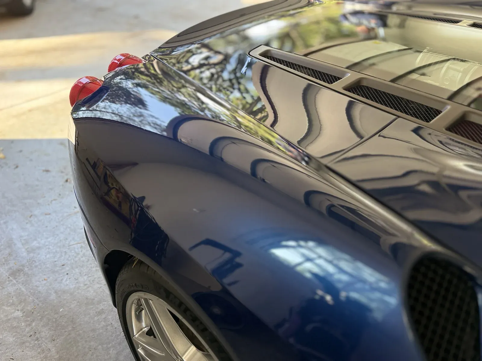 Glossy reflections on a blue Ferrari rear deck after detailing